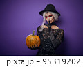 Witch with grey hair whispering in Halloween costume 95319202