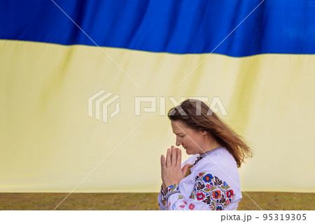 Prayer for Ukraine young woman prays for Ukraine near Ukrainian flag Prayer for Ukraine young woman prays for Ukraine near Ukrainian flag 95319305