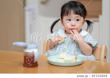 パンを手づかみ食べする1歳の女の子 95320009