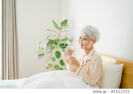 寝室で水を飲むシニア女性 95322252