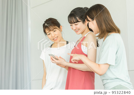 スポーツジムでスマホを見る笑顔のスポーツウェアのアジア人の女性達 95322840