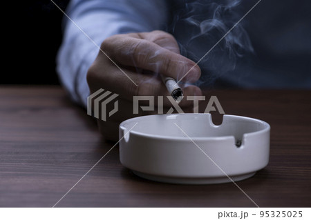 喫煙する男性が手に持っているタバコ 95325025