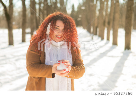 Fat caucasian woman playing snowballs in the park.  95327266