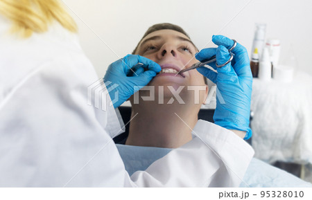 Installation of braces, bridges and a dental plate to correct teeth. An orthodontist installs a bracket system on an uneven jaw. Implants and smile correction. Concept of working in the dentist office Installation of braces, bridges and a dental plate to correct teeth. An orthodontist installs a bracket system on an uneven jaw. Implants and smile correction. Concept of working in the dentist office 95328010