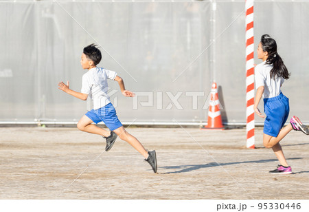 学校の校庭を走っている小学生の男の子と女の子 95330446