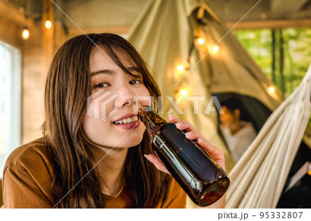 キャンプでビールを片手に微笑む若い女性 95332807