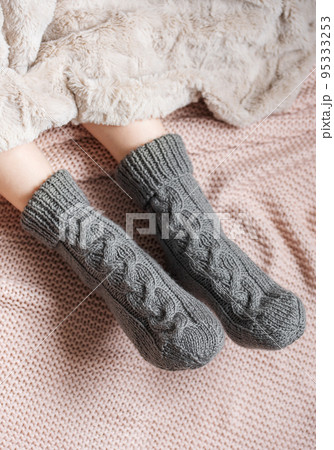 Legs of a young girl in cozy knitted socks 95333253