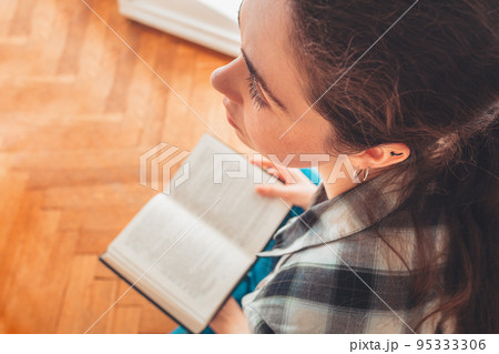 A student reads a book. View from the top, over the head. Concept of reading and learning A student reads a book. View from the top, over the head. Concept of reading and learning 95333306