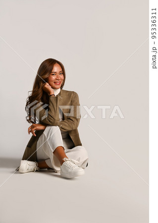 Portrait of beautiful young woman in stylish jacket sitting on white background. Autumn fashion concept 95336311