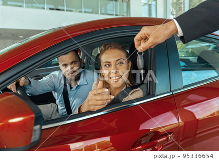 Young couple sitting inside new car and holding keys to it. Concept for car rental 95336654