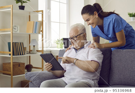 Nurse shows old man how to use apps on digital tablet to monitor his health and how to read e-books Nurse shows old man how to use apps on digital tablet to monitor his health and how to read e-books 95336968