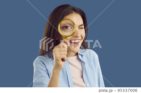 Funny woman with eye enlarged by magnifying glass looking through and searching for something Funny woman with eye enlarged by magnifying glass looking through and searching for something 95337006