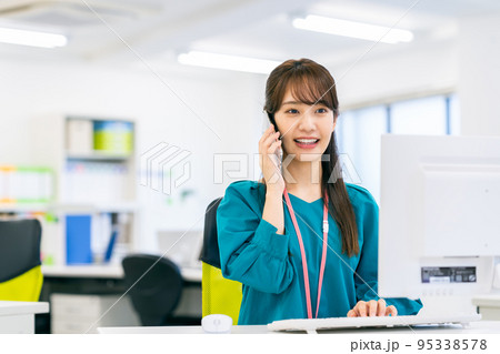 オフィスで電話する若いビジネスウーマン オフィスで電話する若いビジネスウーマン 95338578