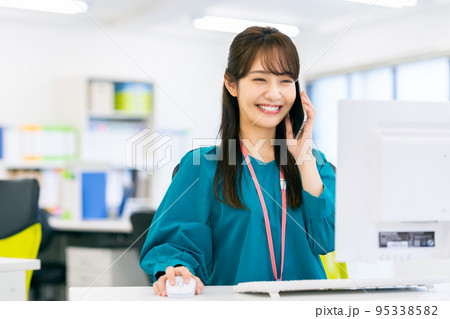 オフィスで電話する若いビジネスウーマン オフィスで電話する若いビジネスウーマン 95338582