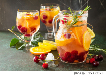 Homemade refreshing wine sangria or punch with fruits in glasses. Sangria cocktails with fresh fruits, berries and rosemary. On a stone or slate background, with a jug and ingredients. Copy space. Homemade refreshing wine sangria or punch with fruits in glasses. Sangria cocktails with fresh fruits, berries and rosemary. On a stone or slate background, with a jug and ingredients. Copy space. 95339972