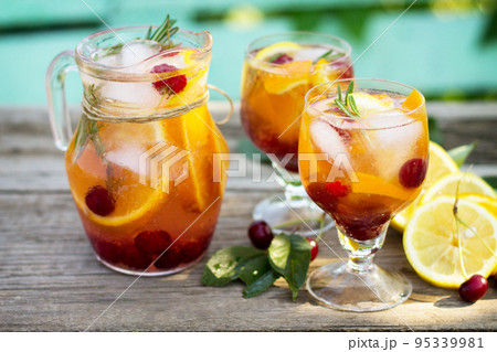 Homemade refreshing drink. Wine sangria or punch with fruits in glasses, cocktails with fresh fruits, berries and rosemary on a wooden rustic table. 95339981