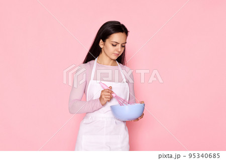 woman holding whisk and bowl with eggs 95340685