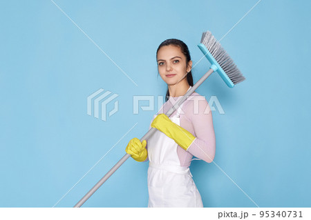 woman in gloves and cleaner apron holding broom woman in gloves and cleaner apron holding broom 95340731