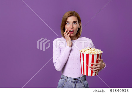 woman watching movie film, holding bucket of popcorn woman watching movie film, holding bucket of popcorn 95340938