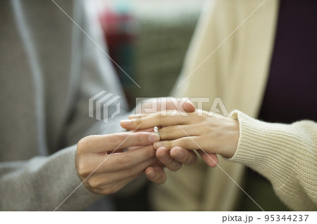 プロポーズイメージ　指輪をはめるカップルの手元 95344237