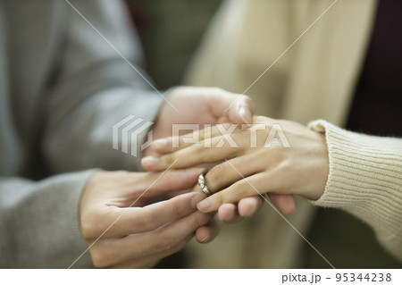 プロポーズイメージ　指輪をはめるカップルの手元 95344238