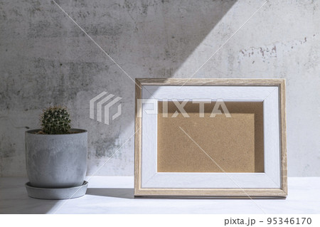 小さな植木鉢に植えたサボテンと写真立て 95346170
