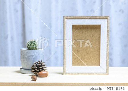 小さな植木鉢に植えたサボテンと写真立て 95346171