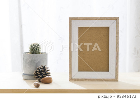 小さな植木鉢に植えたサボテンと写真立て 95346172