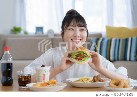チートデイ　ジャンクフードを前に微笑む若い女性 95347139