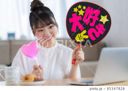 推し活 ライブ動画を見ながらうちわを振って推しを応援する若い女性 推し活 ライブ動画を見ながらうちわを振って推しを応援する若い女性 95347826