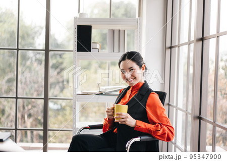 Relax business woman with coffee cup in office with window light. Relax business woman with coffee cup in office with window light. 95347900