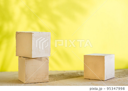 Mockup. Three textured cubes on a beige surface on a yellow background with plant shadows. Mockup. Three textured cubes on a beige surface on a yellow background with plant shadows. 95347998