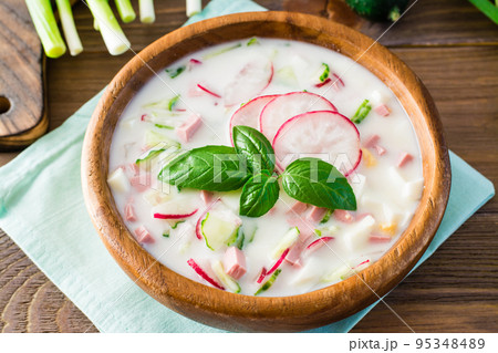 Russian kitchen. Okroshka - cold soup with vegetables, sausages and herbs on kefir. Rustic style. Close-up 95348489