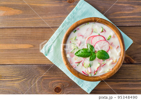 The national Russian dish is okroshka. Cold soup with vegetables and herbs on kefir. Rustic style. Top view 95348490