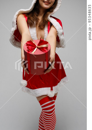 Beautiful happy woman holding a Christmas gift Beautiful happy woman holding a Christmas gift 95348635