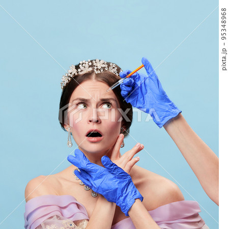 Human hands in gloves making beauty injections to shocked scared young woman in vintage dress and tiara. Eras comparison, anti-aging procedures, skin care concept 95348968