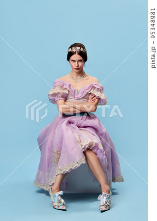 Resentment. Emotional girl in lilac color medieval dress as young queen or princess looking at camera, giving mean look. Eras comparison, beauty, art, emotions 95348981