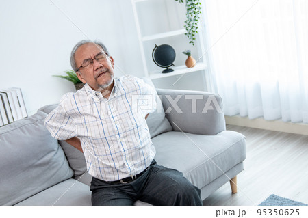 An agonizing senior man is holding his back due to back pain. An agonizing senior man is holding his back due to back pain. 95350625