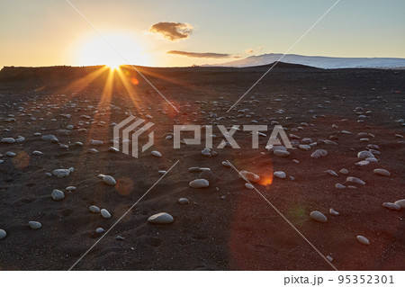 Iceland landscape black sand beach with stones and sunset flare Iceland landscape black sand beach with stones and sunset flare 95352301
