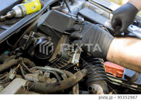 Mechanic hand is replacement car air filter into car engine in service center 95352967