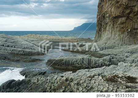 rocky seashore formed by columnar basalt against the backdrop of a stormy sea, coastal landscape of the Kuril Islands rocky seashore formed by columnar basalt against the backdrop of a stormy sea, coastal landscape of the Kuril Islands 95353502