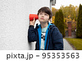 A little curious caucasian boy overheard a conversation through the wall using a cup. Human face expression close up portrait. 95353563