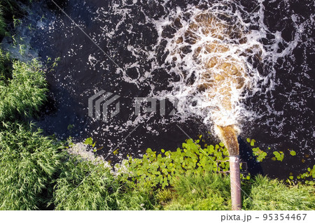 pollution enters the river. Dirty water flows from the pipe into the river. 95354467