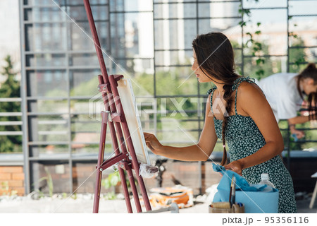 Young woman artist paints with a spatula on the canvas 95356116