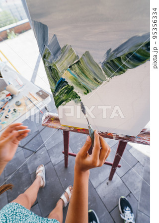 Close-up of woman's hand applying paint to a canvas Close-up of woman's hand applying paint to a canvas 95356334