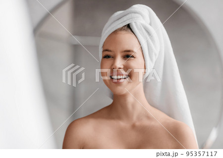 Beauty skincare. Woman looking at herself in mirror and smiling, doing morning beauty routine in bathroom Beauty skincare. Woman looking at herself in mirror and smiling, doing morning beauty routine in bathroom 95357117