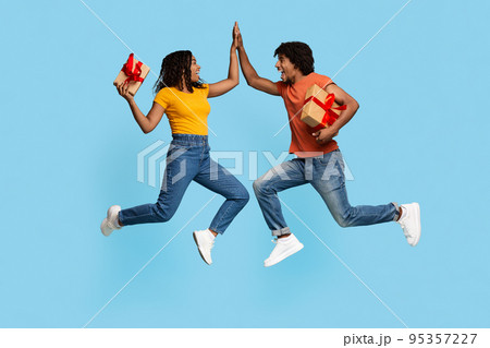Happy man and woman with gift boxes giving high five Happy man and woman with gift boxes giving high five 95357227