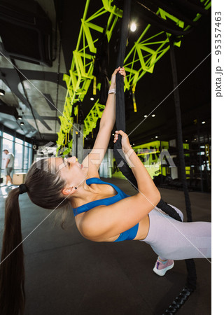 Young woman is climbing a rope in the gym 95357463