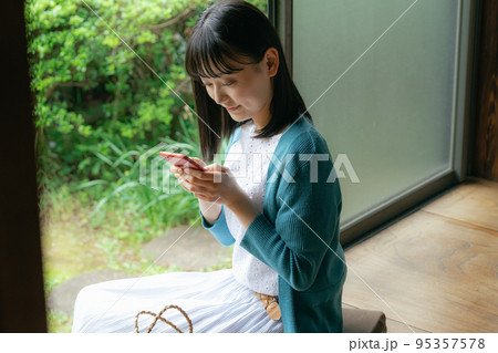 縁側でスマホを見る若い女性 縁側でスマホを見る若い女性 95357578