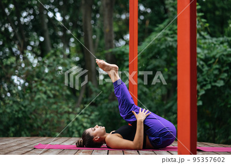 Lying on a back, young beautiful woman bends her legs to the chest Lying on a back, young beautiful woman bends her legs to the chest 95357602